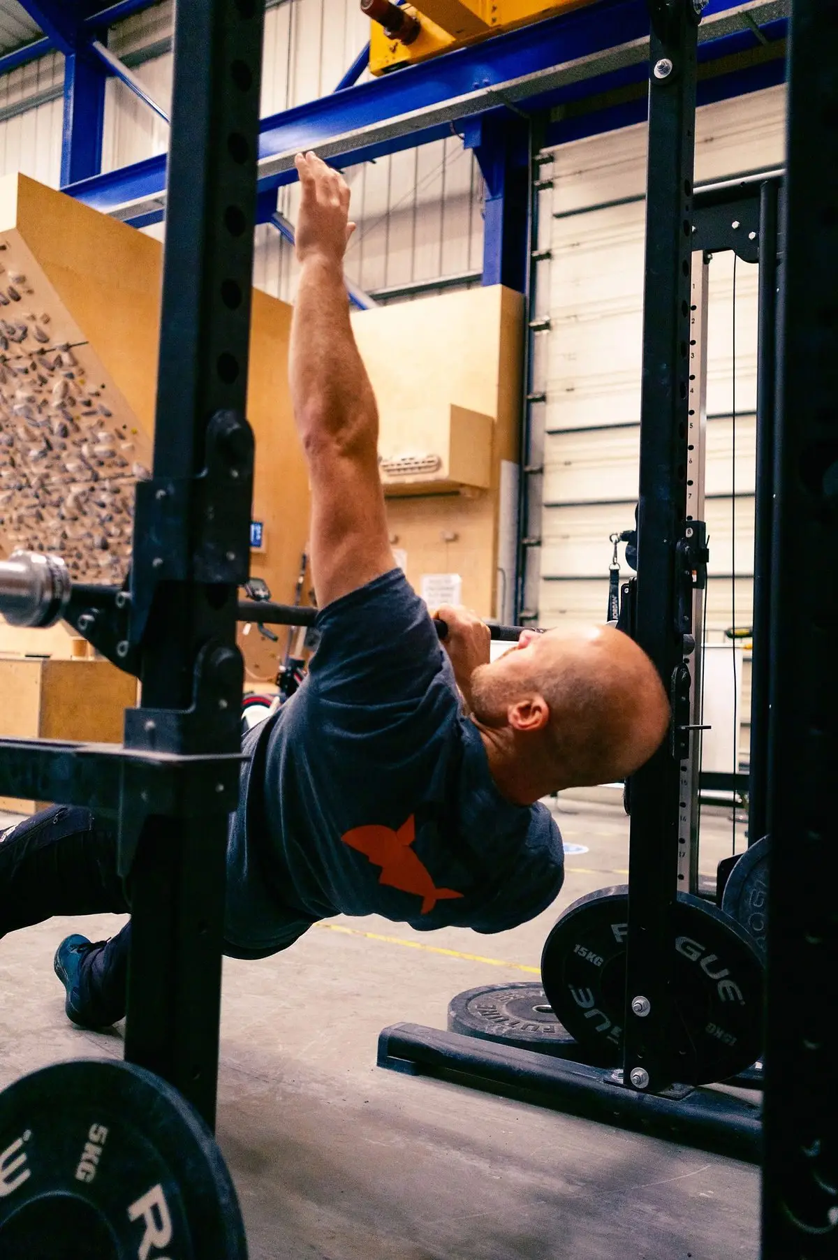 Demonstration of a single-arm reclined pull up using a weight rack and barbell.
